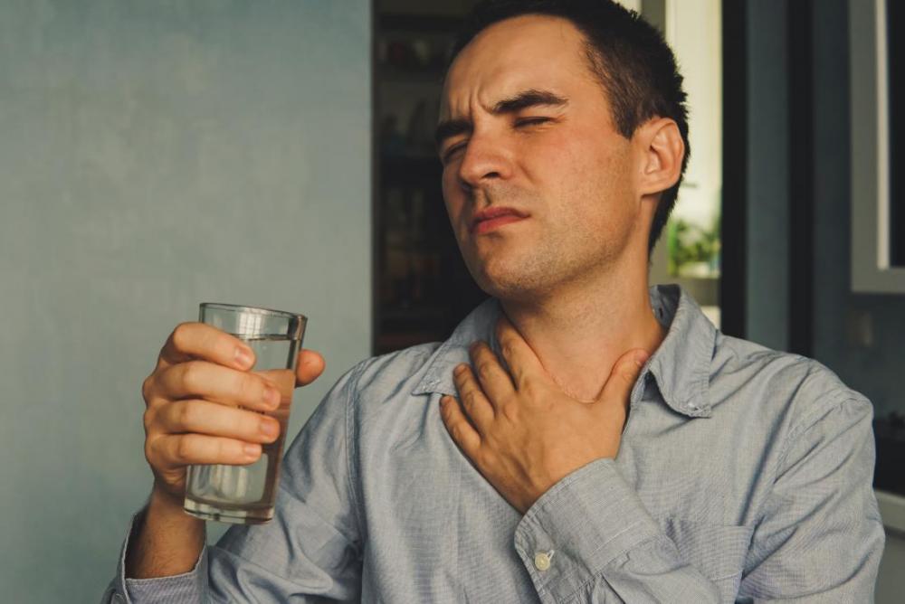 mn-with-dry-throat-clutching-his-neck-in-pain-and-holding-a-glass-of-water.jpg